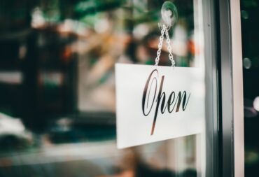 Open sign hanging in a storefront window