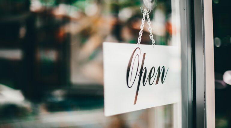 Open sign hanging in a storefront window